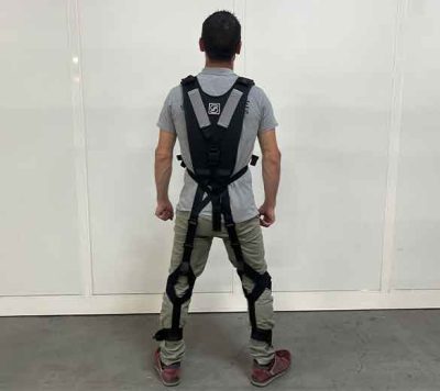 Homme portant un exosquelette dans un atelier.